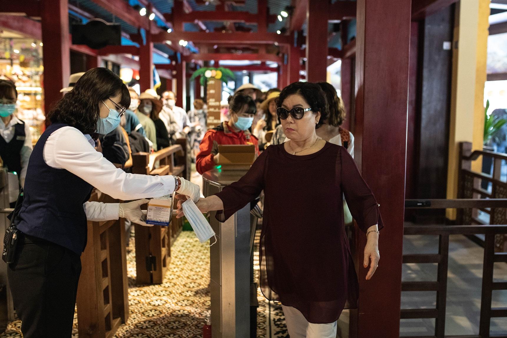 Nhân viên tại Bà Nà Hills phát khẩu trang miễn phí và hướng dẫn du khách đeo khẩu trang đúng cách