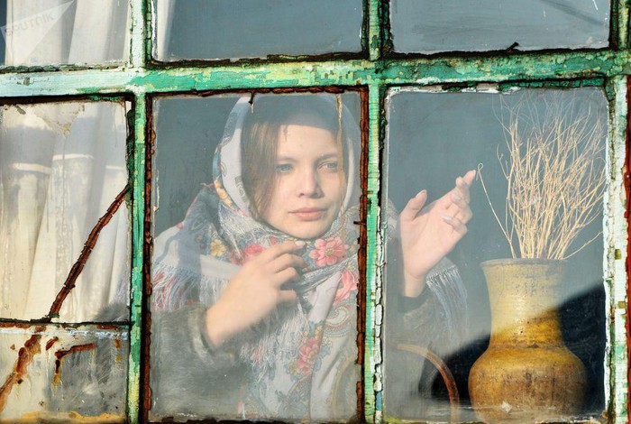 Một bé gái nhìn ra ngoài cửa sổ trong ngôi nhà ở làng Chernorechye, vùng Chelyabinsk.