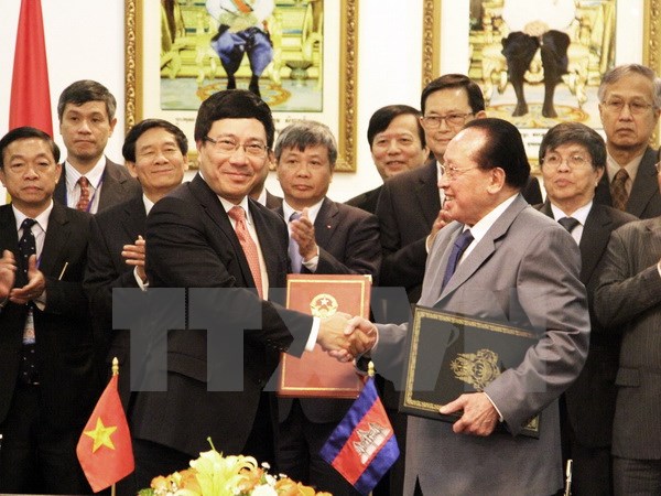 Phó Thủ tướng Phạm Bình Minh (trái) trao đổi Biên bản Thỏa thuận của Kỳ họp thứ 13 với Phó Thủ tướng Campuchia Hor Namhong. (Ảnh: TTXVN)