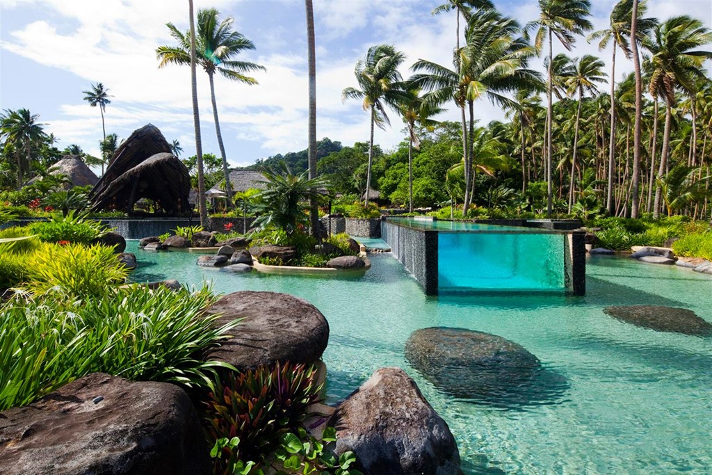 Laucala Island, Fiji: Bể bơi ở khu nghỉ dưỡng Laucala Island có thiết kế độc đáo, với phần bể dưới theo kiểu tự nhiên và phần bể trên có thành kính trong suốt, nằm giữa khu vườn xanh tươi, đầy nắng.