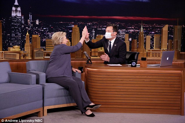 Người dẫn chương trình Jimmy Fallon đeo khẩu trang y tế khi mở màn cuộc trò chuyện phỏng vấn với ứng viên tổng thống đảng Dân chủ Hillary Clinton trên sóng truyền hình. 