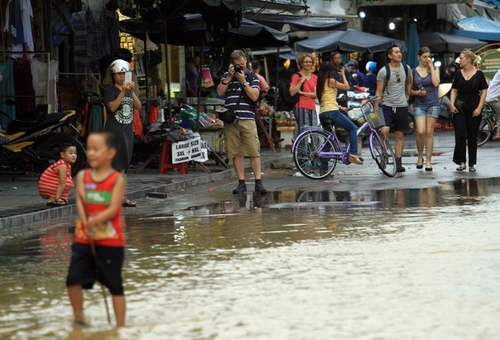 Những đứa trẻ ở Hội An đã quá quen với cảnh ngập lụt, nhảy múa tung tăng dưới lòng đường ngập, khiến khách nước ngoài thích thú bấm máy ảnh.