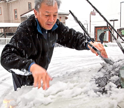 Một người đàn ông cào tuyết khỏi xe ở Koshu, tỉnh Yamanashi. Thời tiết bất thường khiến giao thông ở nhiều nơi bị đình trệ. Cơ quan khí tượng Nhật Bản cũng cảnh báo người dân cẩn trọng khi di chuyển trên những con đường trơn, dưới những đường dây điện hay cây phủ tuyết và các ngôi nhà kính lợp mái nhựa có thể bị sập. Ảnh: Asahi Shimbun