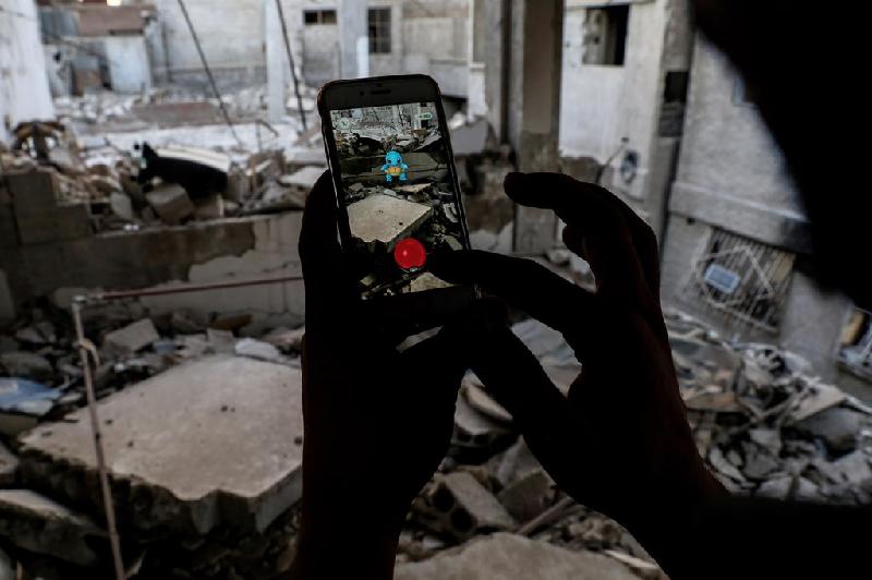 Một thanh niên Syria chơi bắt thú ảo Pokemon Go ở giữa một tòa nhà đổ nát do nội chiến ở Douma, phía đông thủ đô Damascus ngày 23/7. Trò chơi này gây sốt trên cả thế giới vào mùa hè năm 2016.