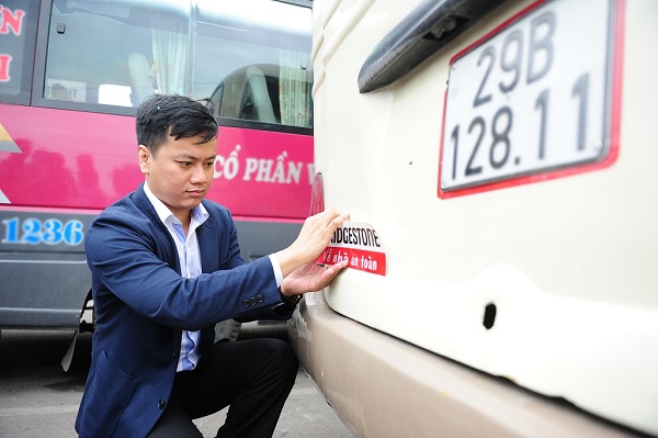 Đại diện Bridgestone Việt Nam dán bộ phản quang cho xe khách tại Bến xe Giáp Bát (Hà Nội)