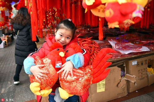 Một cô bé ôm hai con gà trống bằng bông tại một khu chợ ở Miên Dương, tỉnh Tứ Xuyên (Ảnh: IC)