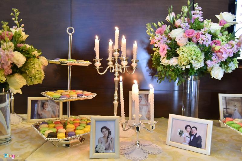 Không gian tiệc cưới trang trí sang trọng với hoa tươi, nến, bánh ngọt và ảnh của cô dâu - chú rể. 