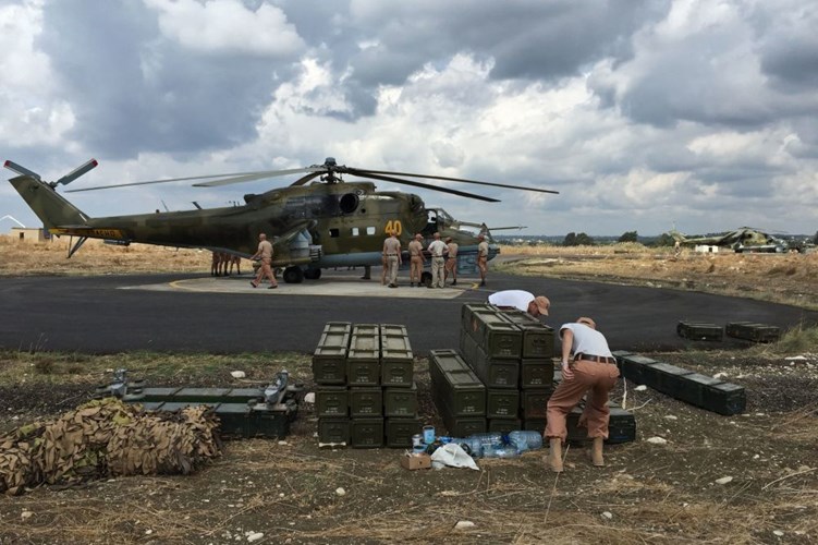 Các kỹ sư mặt đất đứng gần trực thăng Mi-24 ở khu căn cứ. Ảnh Sputnik