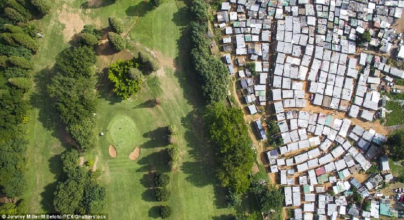 Tại Thành phố Durban của Nam Phi, Sân gôn Papwa Sewgolum (bên trái) nằm cách các ngôi nhà tạm bợ lợp thiếc chỉ vài mét. Hai nơi được chia cách bằng bức tường bê tông thấp. Ảnh: Johnny Miller.