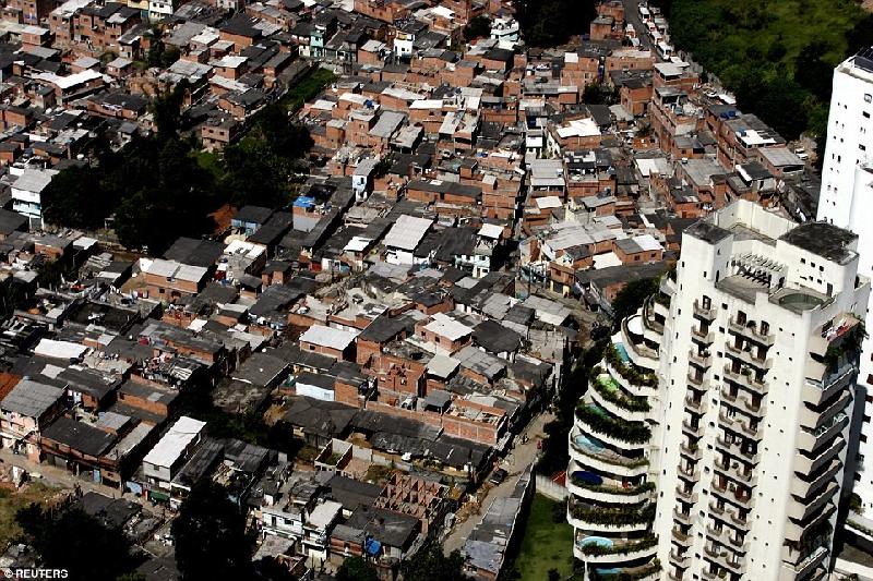 Khu ổ chuột Paraisopolis (trái) với khoảng 60.000 cư dân nằm ngay cạnh khu căn hộ đầy đủ tiện nghi được trang bị bể bơi (bên phải) trong khu phố Morumbi của Sao Paulo, Brazil. Ảnh: 
