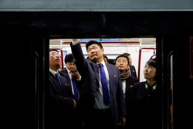 Phóng viên Reuters chụp lại cảnh công chức Triều Tiên mặc đồng phục, đeo huy hiệu đảng Lao động qua cửa kính tàu điện hôm 14/4.