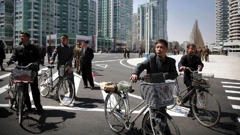Người dân Bình Nhưỡng dắt xe đạp đi trên tuyến phố mới.