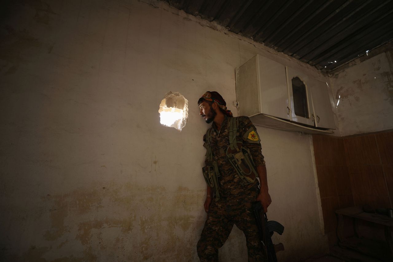 Chiến binh SDF đang quan sát bên ngoài từ trong một ngôi nhà