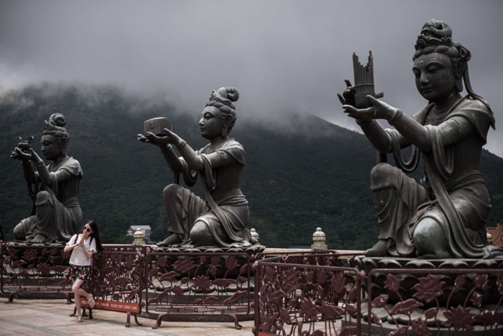 Du khách tạo dáng bên các bức tượng bên trong tu viện Po Lin trên đảo Lantau. Ảnh:  AFP.