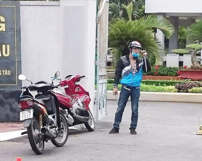 Nguyễn Song Phương cầm mã tấu đứng trước cổng hội trường Thành ủy Vũng Tàu. Ảnh: 