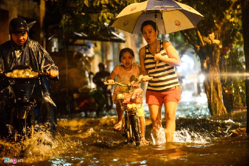 Mẹ con bé Vũ Quỳnh nhà ở ngay đây vẫn bất ngờ khi gặp phải mưa lớn. Hai người đi nép vào lề đường tránh ngập.
