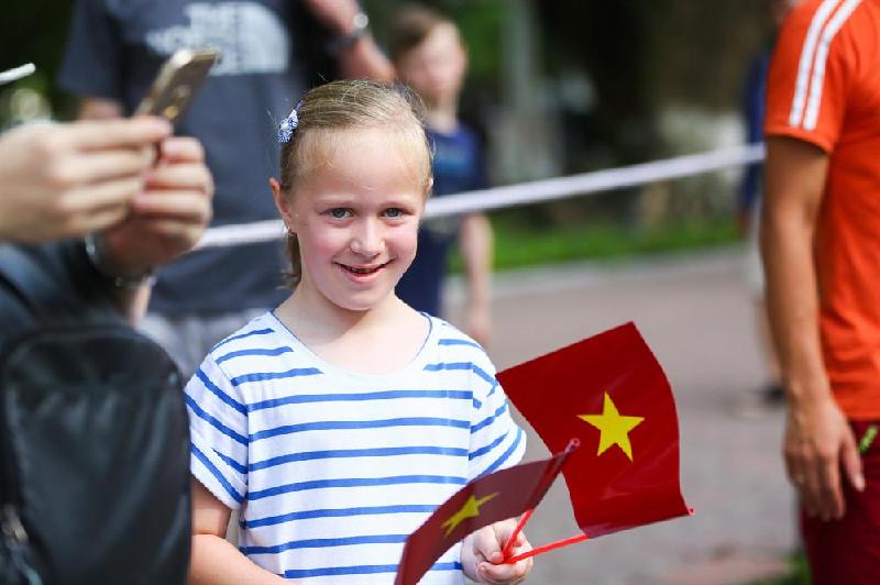 Bạn nhỏ người nước ngoài thích thú cầm cờ Tổ quốc Việt Nam.