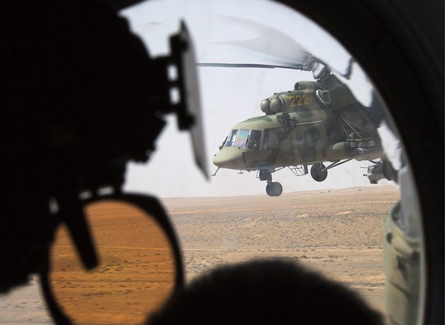 Một binh sĩ Nga đang đứng gác trong khi một trực thăng quân sự bay trên bầu trời Palmyra