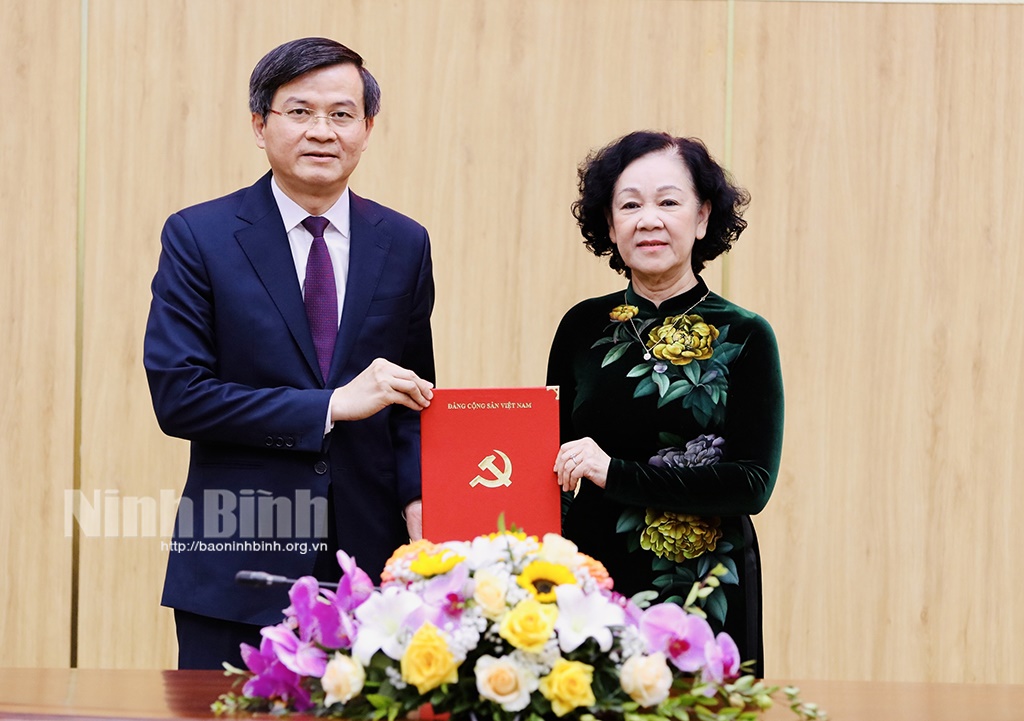 Bà Trương Thị Mai, Ủy viên Bộ Chính trị, Thường trực Ban Bí thư, Trưởng Ban Tổ chức Trung ương trao Quyết định và tặng hoa chúc mừng ông Đoàn Minh Huấn - ảnh báo NB