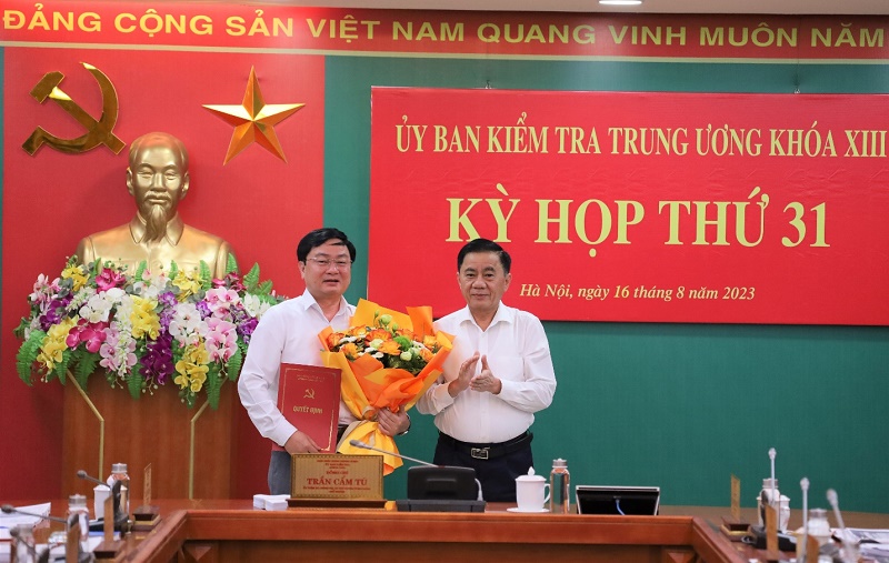Ông Trần Cẩm Tú, Ủy viên Bộ Chính trị, Bí thư Trung ương Đảng, Chủ nhiệm UBKT Trung ương trao quyết định và tặng hoa chúc mừng ông Nguyễn Văn Quyết.