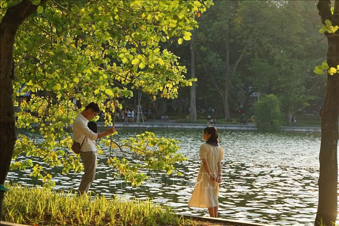 Các bạn trẻ lưu lại khoảng khắc mùa Thu Hà Nội tại hồ Hoàn Kiếm. Ảnh: Khánh Hòa/TTXVN