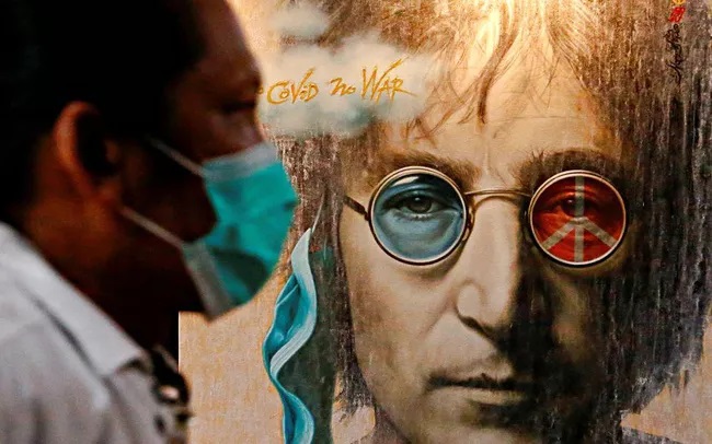Một du khách đeo khẩu trang che mặt đi ngang qua tác phẩm nghệ thuật vẽ John Lennon trong một cuộc triển lãm, giữa lúc dịch bệnh COVID-19 bùng phát ở Jakarta, Indonesia, ngày 15 tháng 10 năm 2020. (Ảnh: REUTERS / Ajeng Dinar Ulfiana)