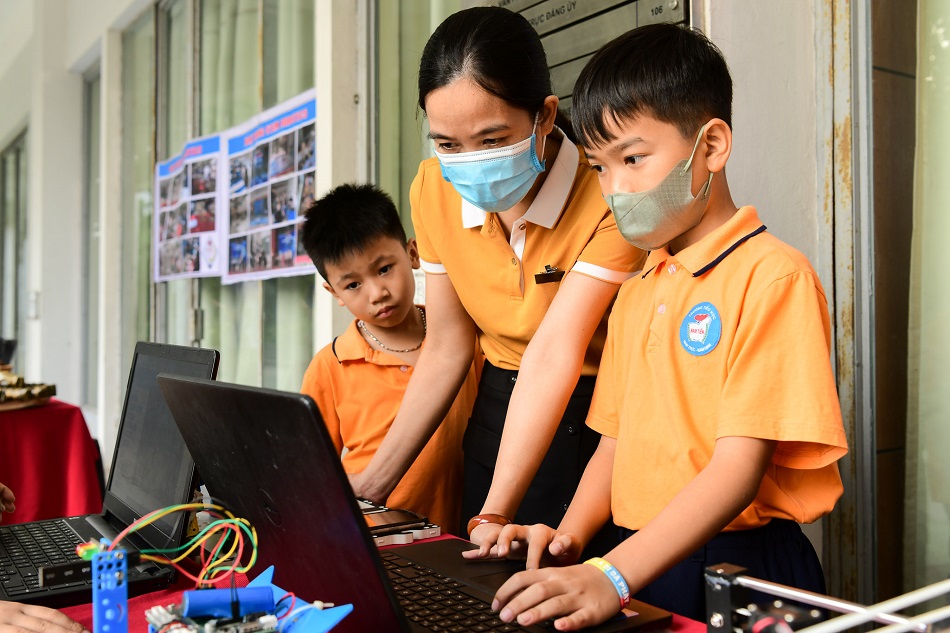 Nhóm học sinh trường tiểu học ở Nam Định trải nghiệm robot bên lề tọa đàm STEM tại Hội trường C2, Đại học Bách khoa Hà Nội. Ảnh: CCPR.