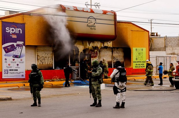 Lực lượng an ninh Mexico bên ngoài một cửa hàng tiện lợi bị thiêu rụi bởi những kẻ tấn công chưa rõ danh tính ngày 11/8. (Nguồn: AP)