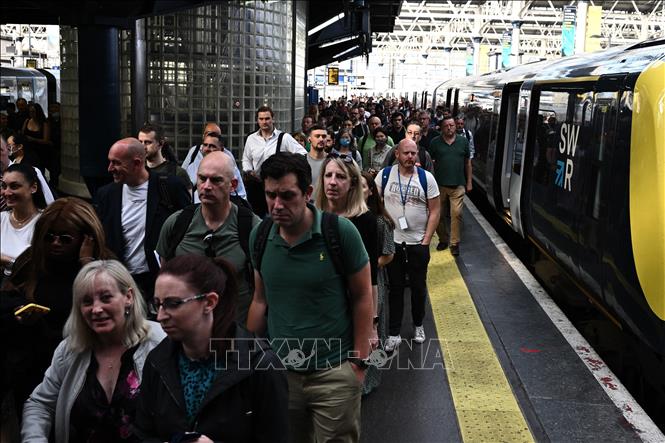 Hành khách rời khỏi tàu tại nhà ga Waterloo ở thủ đô London, Anh, khi các công nhân tiến hành đình công kêu gọi tăng lương, ngày 21/6/2022. Ảnh: AFP/TTXVN