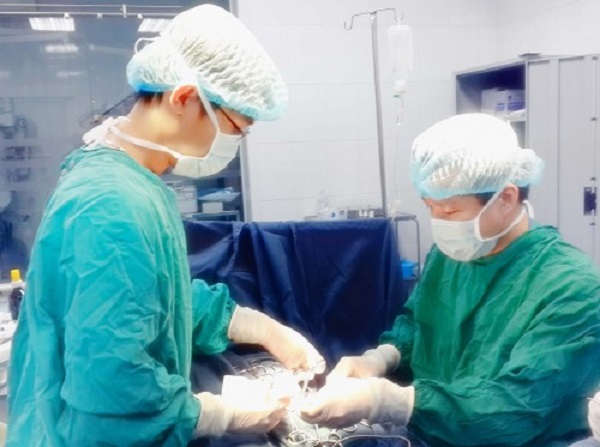 PGS Trần Ngọc Sơn ( người đứng bên phải) trong quá trình phẫu thuật cho bé Thanh Bình ( Ảnh: Bác sĩ cung cấp)