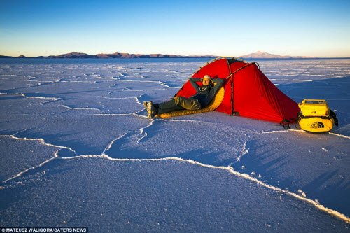 Chàng trai 29 tuổi nằm nghỉ bên ngoài lều của mình trên cánh đồng muối Salar de Uyuni lúc bình minh.