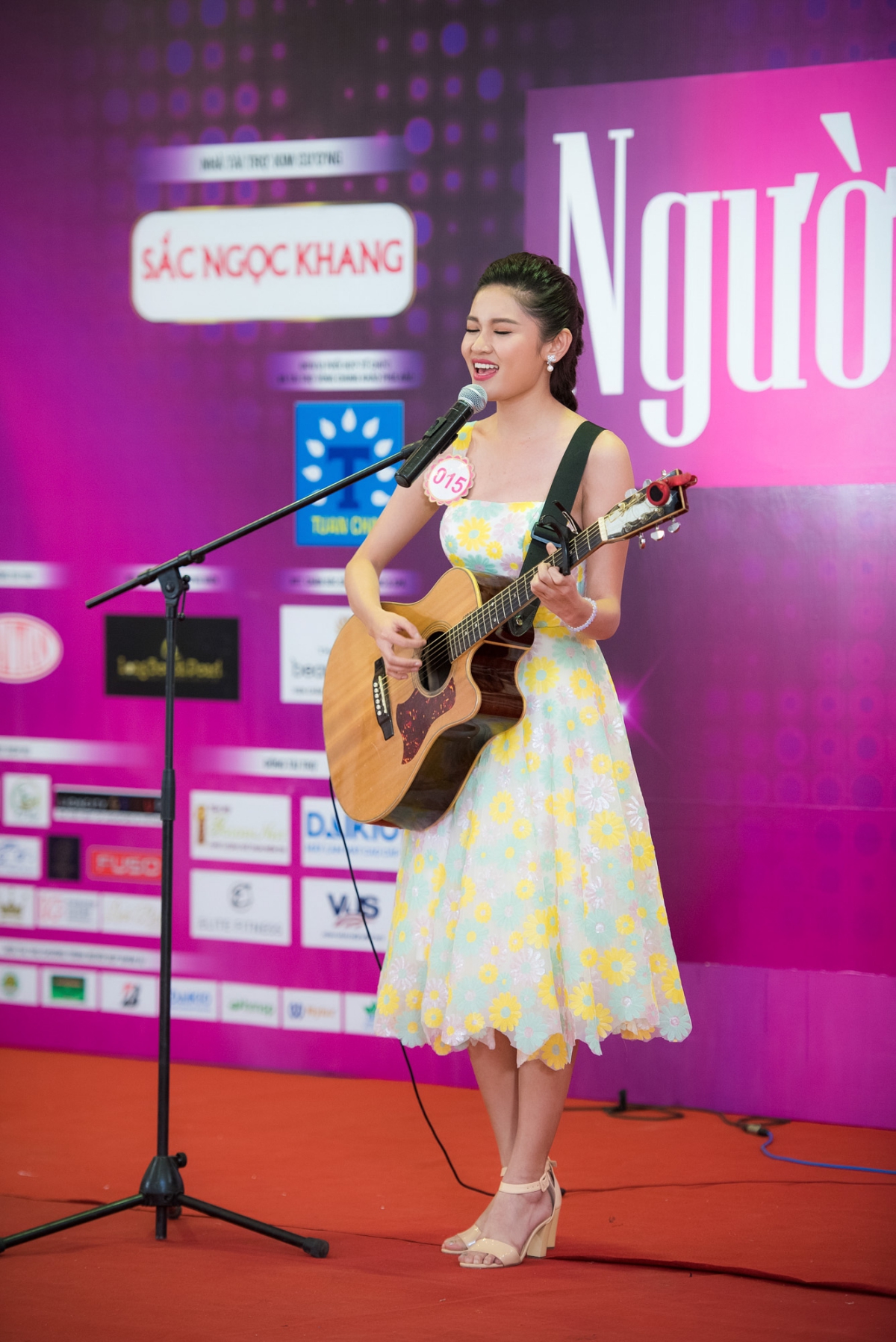 Huỳnh Thị Thuỳ Dung (SBD 015) mặc váy hoa thanh lịch, vừa đệm đàn guitar vừa thể hiện ca khúc tiếng Anh 