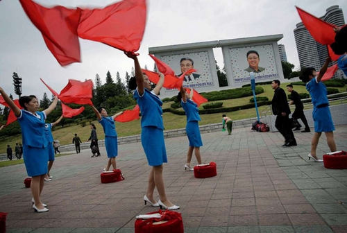 Đội cổ vũ này đứng dưới bức chân dung của cố lãnh tụ Triều Tiên Kim Nhật Thành và Kim Jong Il.