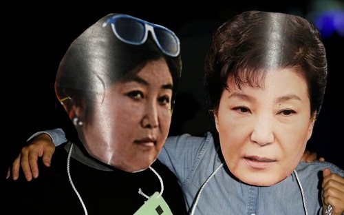 Người biểu tình ở Seoul, Hàn Quốc đeo mặt nạ cắt từ ảnh của bà Choi Soon-sil (trái) và ảnh cuẩ Tổng thống Park Geun-hye - Ảnh: Reuters