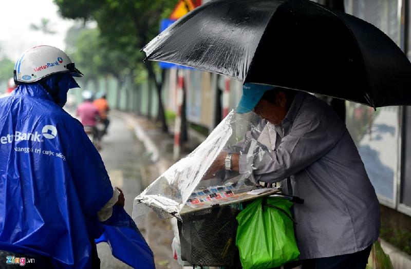Một người bán vé số bên đường Nguyễn Hữu Cảnh phải che hàng của mình để không bị nước mưa làm hỏng.