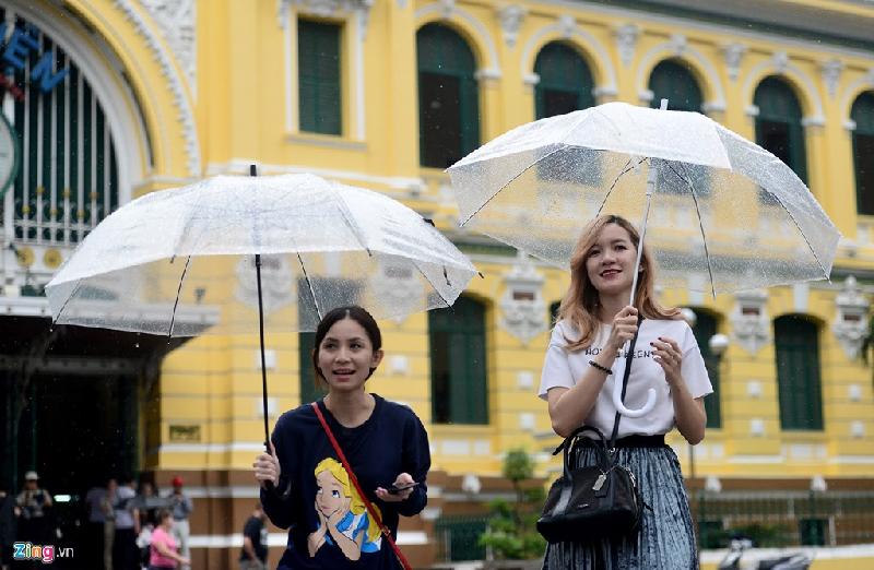 Hai nữ du khách Thái Lan thích thú dạo bước trước bưu điện thành phố giữa trời mưa nhẹ hạt.