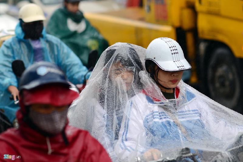 Hai cô gái đèo nhau chung một chiếc áo mưa mỏng bị gió thổi táp vào mặt.