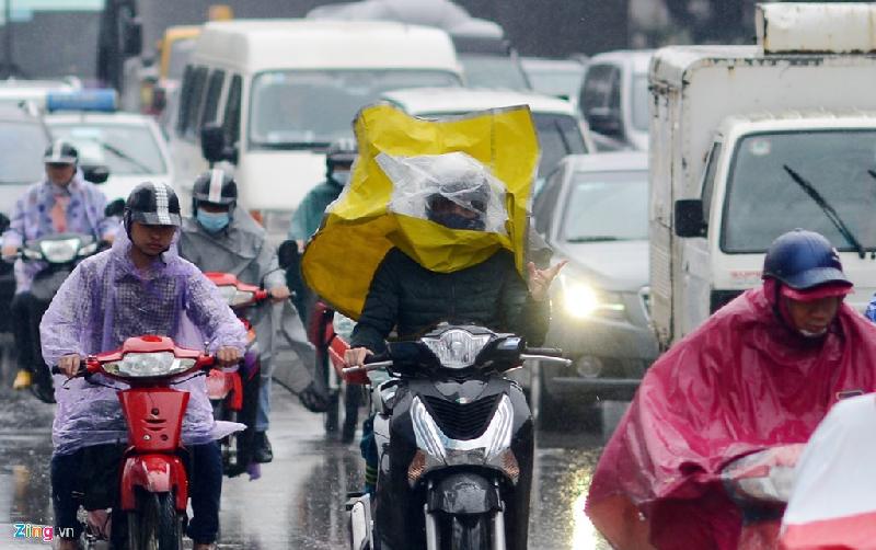 Người phụ nữ khác khi lái xe máy ở tốc độ khoảng 40 km/h giữa dòng người đông đúc đã bị gió hất tung áo mưa che mặt mất vài giây, khá nguy hiểm.