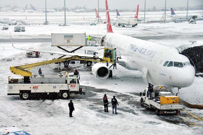 Công nhân hối hả dọn tuyết quanh máy bay của hãng Turkish Airlines đang đậu tại phi trường ở thành phố Istanbul. Ảnh: AP.