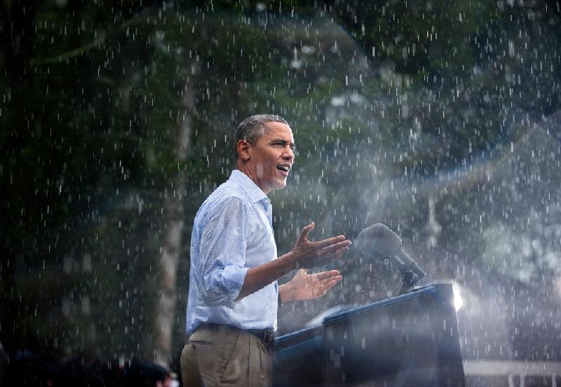 Ngày 14/7/2012, Tổng thống Obama trầm mình trong mưa khi phát biểu vận động tranh cử tại thị trấn Glen Vallen, bang Virginia. Khi đến nơi và thấy rất nhiều người đang chờ mình dưới cơn mưa rào nặng hạt, ông đã hủy buổi họp báo trong nhà và phát biểu ngay để mọi người có thể về nhà. Ảnh: 