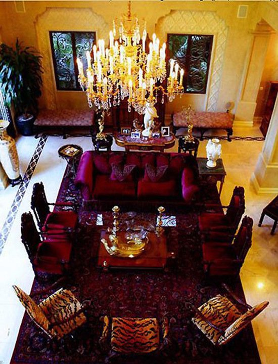 Phòng khách nổi bật với gam màu hồng tím, có ghế ngồi bọc da thú, trần sơn vàng óng ánh và chùm đèn pha lê lộng lẫy.
