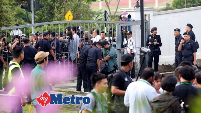 Cảnh sát bố trí đảm bảo an ninh tại tòa án huyện Sepang, thuộc bang Selangor của Malaysia. Báo chí áp sát cửa vào thứ hai của tòa để đưa tin. Theo Channel NewsAsia, khoảng 200 cảnh sát được triển khai bảo vệ an ninh bên ngoài phiên tòa. Luật sư của nghi phạm người Indonesia cho biết ông sẽ không đưa ra lời biện hộ hôm nay do buổi này chỉ là tuyên bố buộc tội các nghi phạm. Ảnh: My Metro.