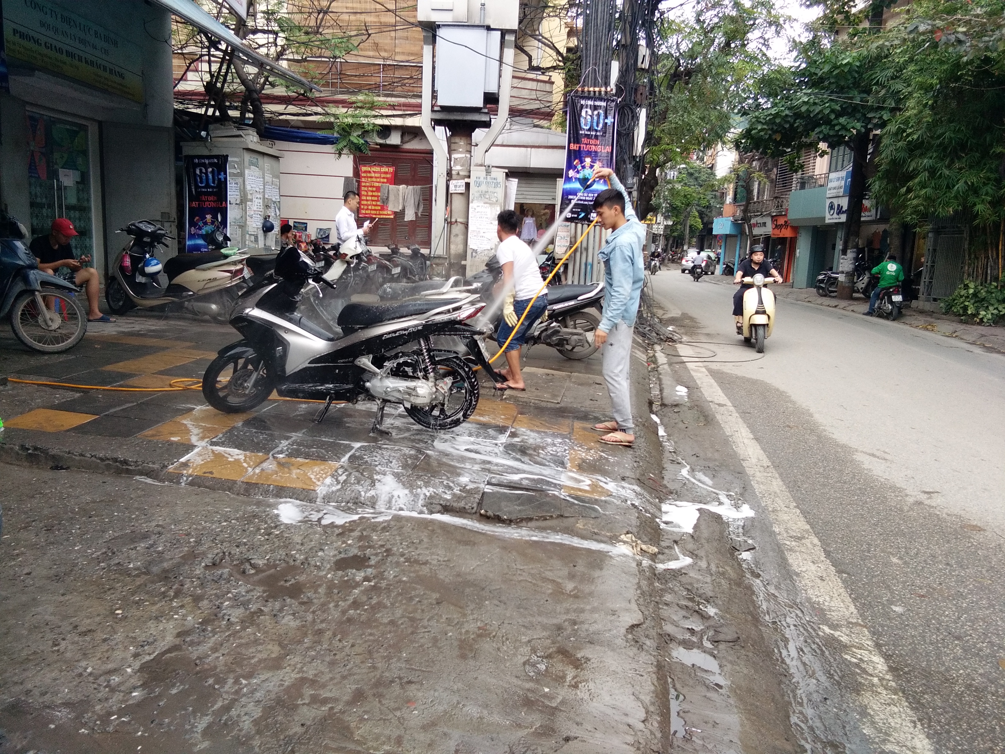 Không những thế quán sửa xe máy còn để hẳn xe máy ra vỉa hè để rửu xe khi phun nước bắn tung tóe vào người đi bộ cũng như người tham gia giao thông.