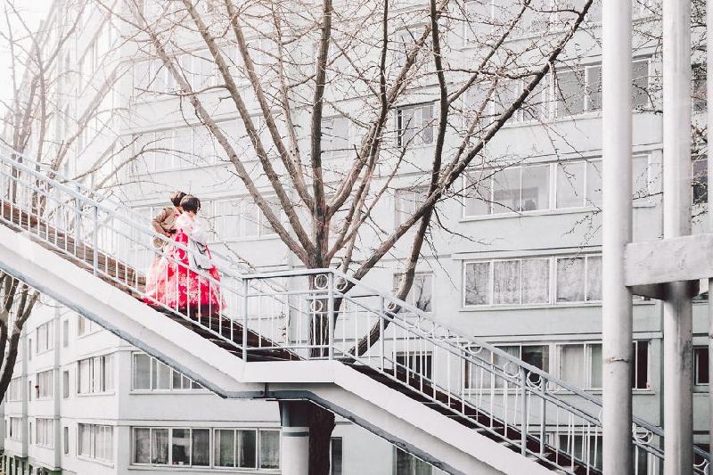 Hai cô gái Triều Tiên với trang phục sặc sỡ trên nền trắng của các tòa nhà.