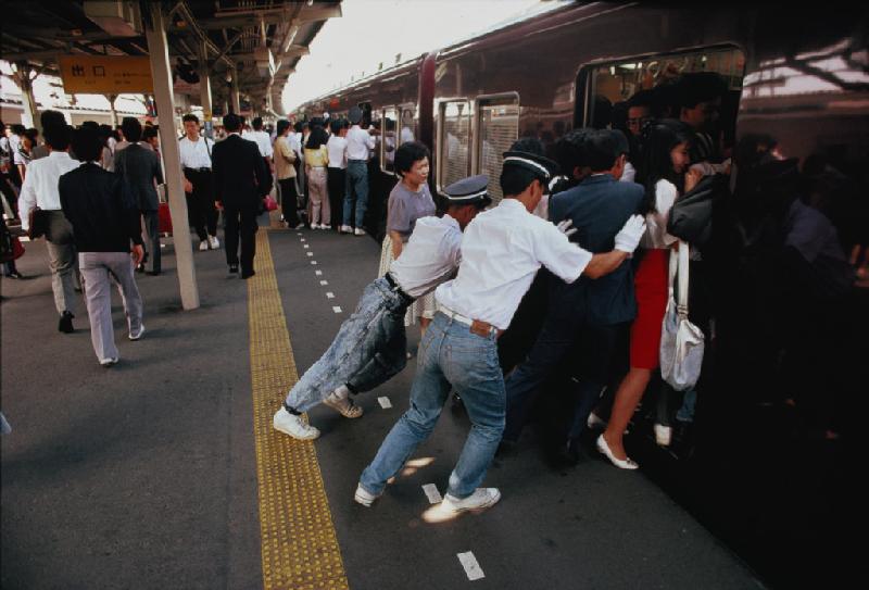 Các nhân viên đường sắt tại nhà ga Honshu ở Tokyo (Nhật Bản) đang cố ép người đi làm hàng ngày vào trong chuyến tàu đông đúc.