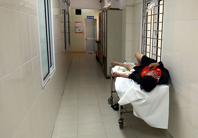 Một bệnh nhân nằm truyền dịch ngoài hành lang bệnh viện. Chai truyền đang vắt tạm bên chấn song cửa sổ