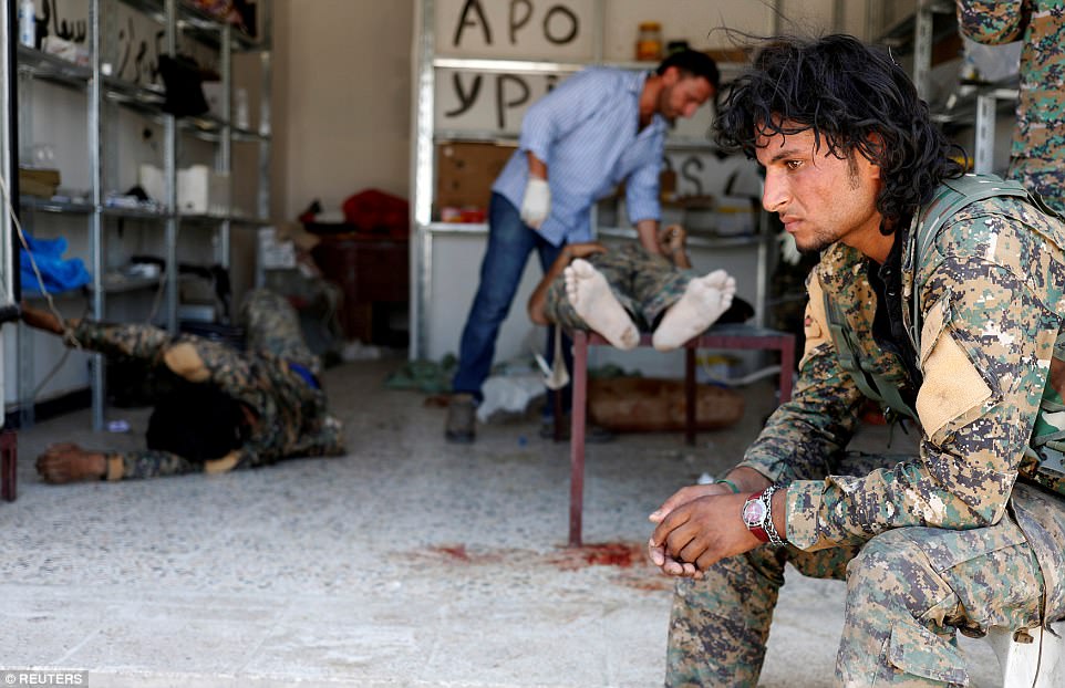 Bức ảnh của phóng viên ảnh Goran Tomasevic: Một chiến binh thuộc Lực lượng Dân chủ Syrai đang ngồi trong một khu vực điều trị y tế tạm thời – nơi các đồng đội của anh đang được cứu chữa. Họ đã bị chiến binh IS bắn tỉa hôm 28/6