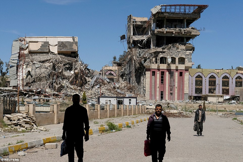Bức ảnh của phóng viên ảnh Marko Djurica: Người dân đi lại trước những gì còn sốt lại của trường Đại học Mosul – nơi đã bị phá hủy và đốt cháy trong một trận chiến với IS hôm 10/4.