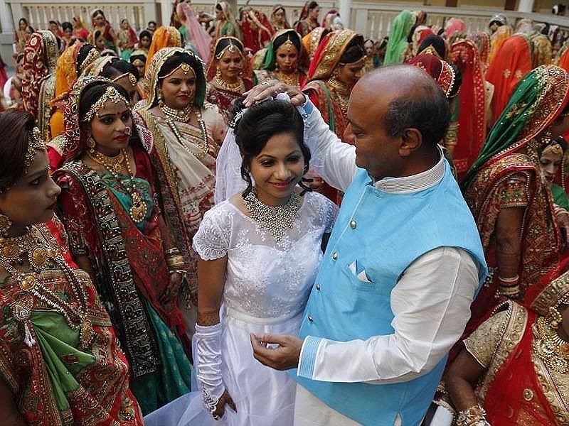 Ông Savani (áo xanh) chúc phúc cho cô dâu theo đạo Cơ Đốc Priyanka Gamit. Ảnh: AP
