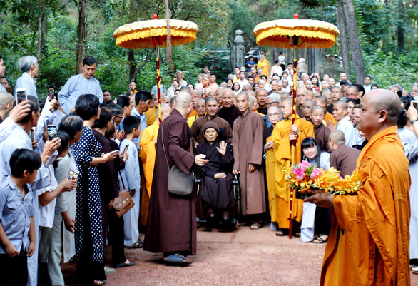 Thiền sư Thích Nhất Hạnh dừng lại trước cổng chùa, đưa tay chào huynh đệ và phật tử